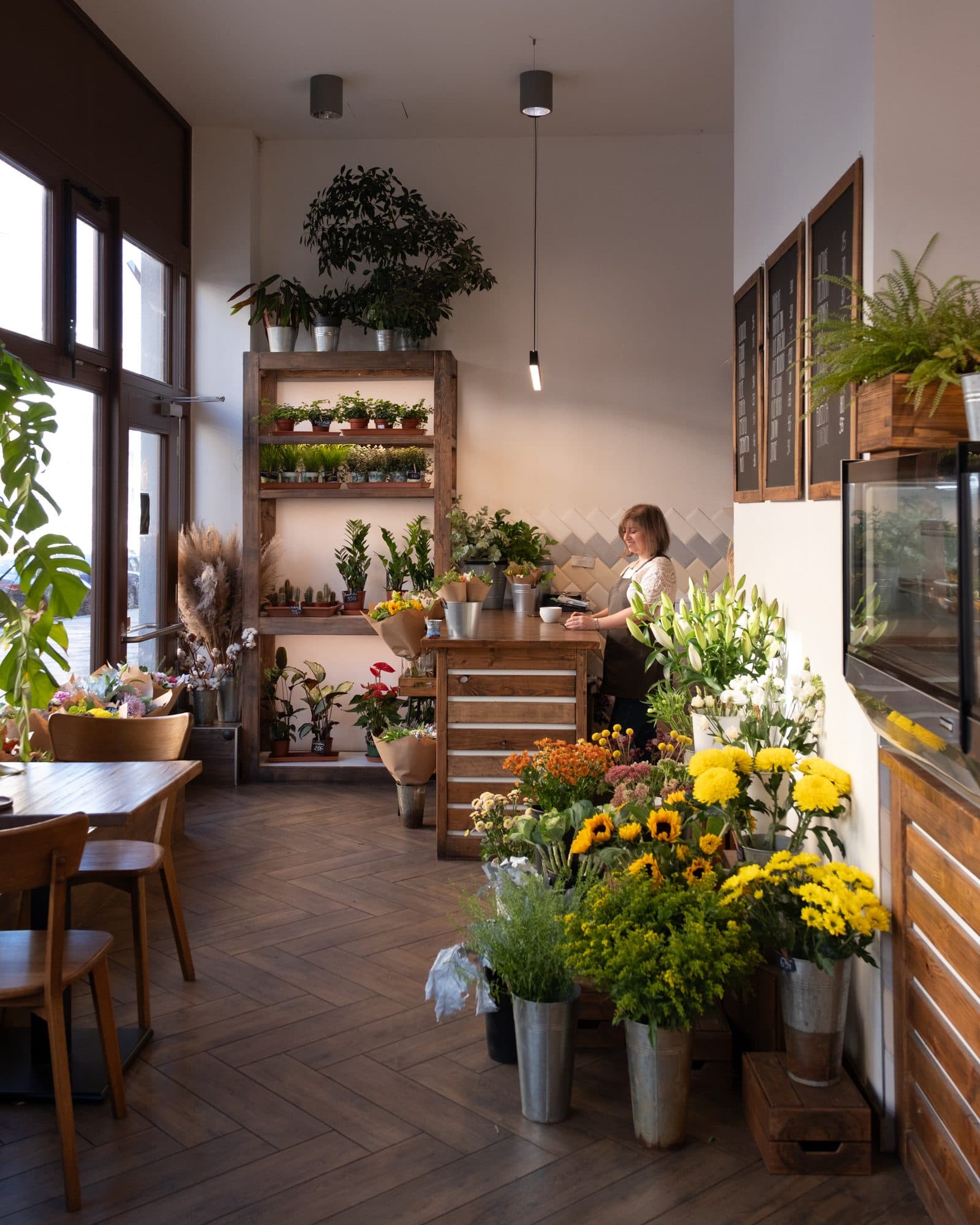 Inside Florista café: wooden counter, shelves of plants and buckets of sunflowers