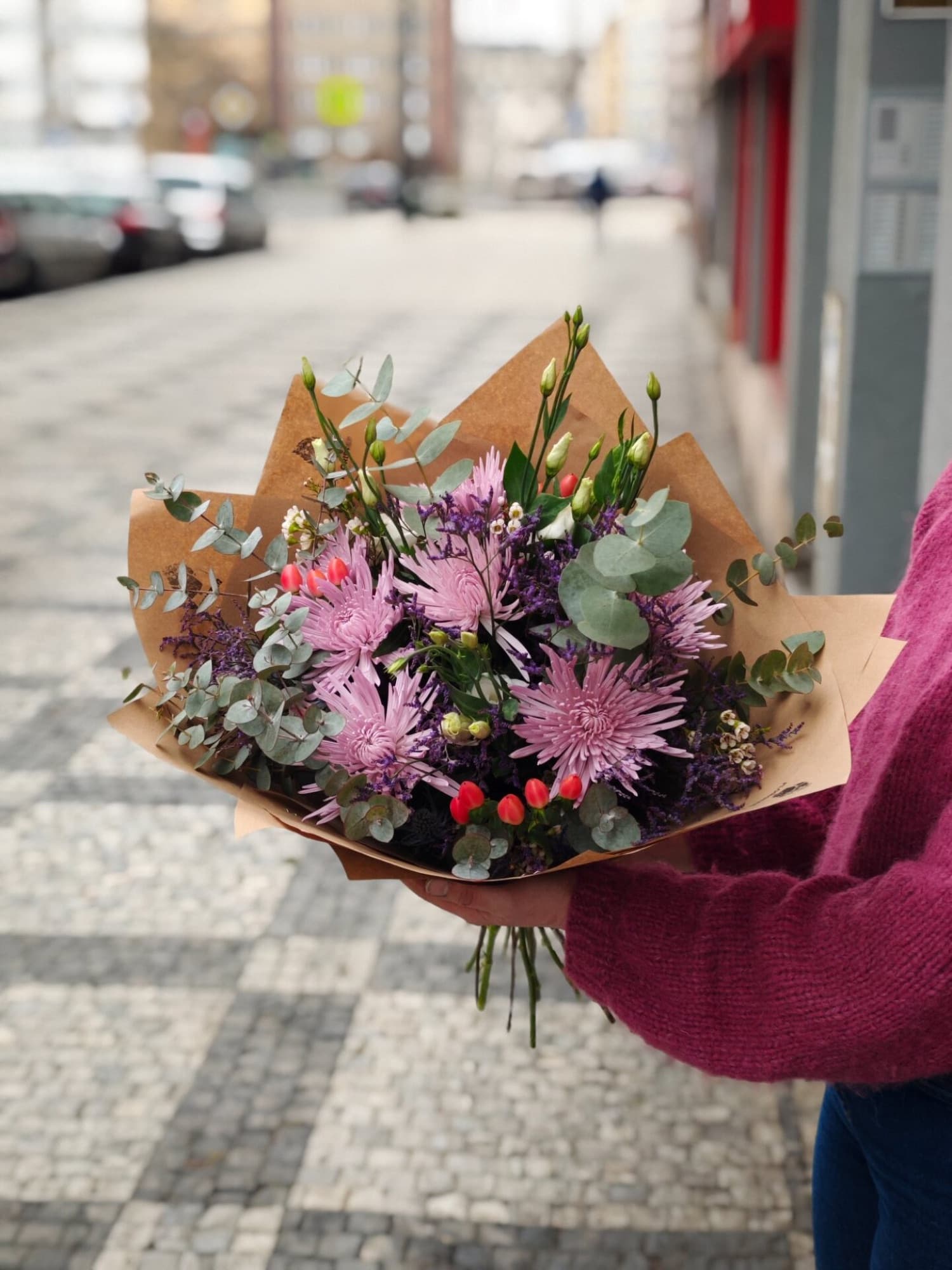 Bouquet of purple chrysanthemums held in hand on a Prague street